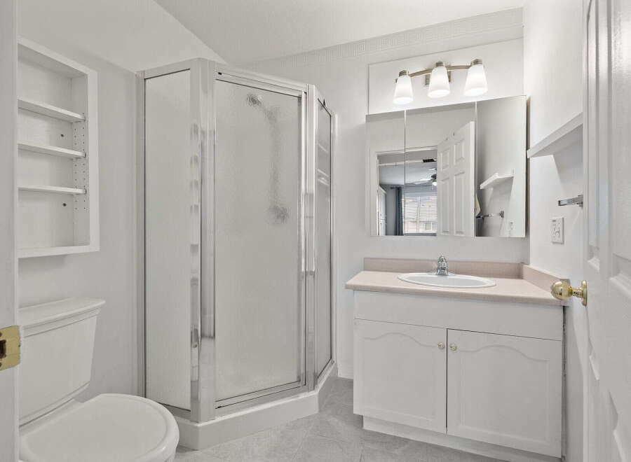 Step into this bright and airy bathroom, featuring a modern glass shower and ample storage.