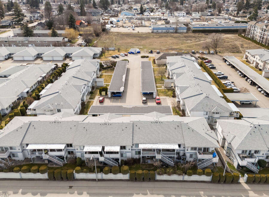 Discover a charming residential complex featuring well-maintained townhouses with gray roofs and white exteriors.
