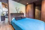 Discover the charm of this beautifully designed bedroom, featuring a cozy bed with a vibrant blue cover and stylish dark pillows.