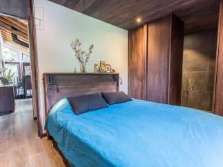 Discover the charm of this beautifully designed bedroom, featuring a cozy bed with a vibrant blue cover and stylish dark pillows.