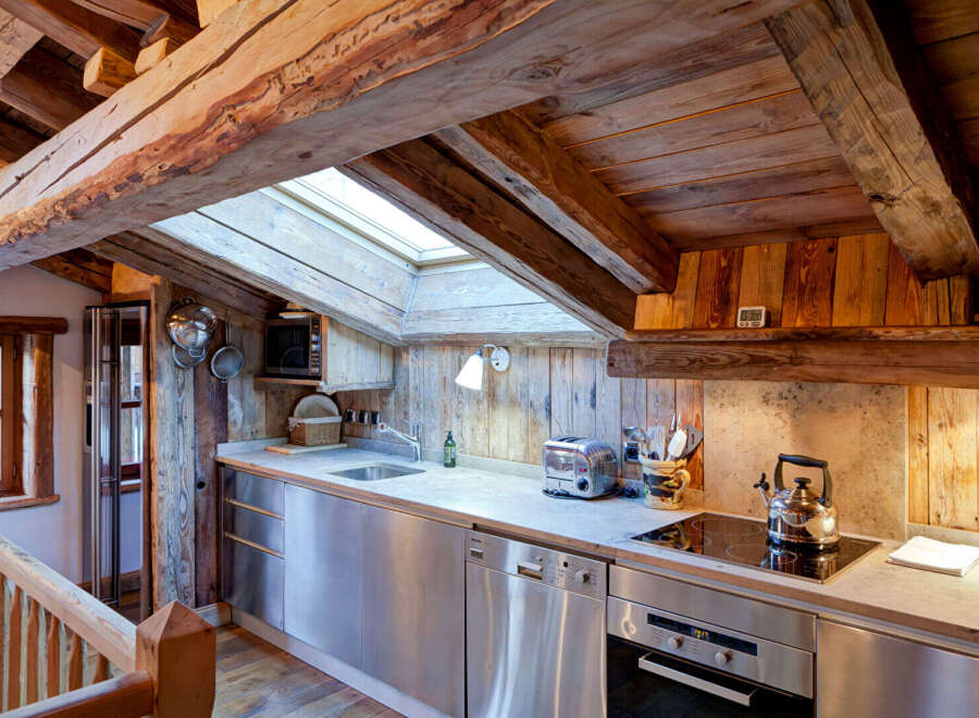 This charming kitchen boasts a rustic design with exposed wooden beams and paneling, creating a warm and inviting atmosphere.