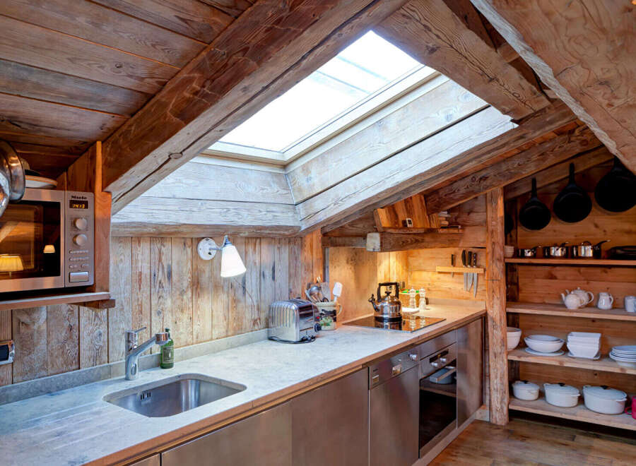 This charming kitchen features a rustic design with exposed wooden beams and a skylight, creating a warm and inviting atmosphere.