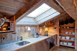 This charming kitchen features a rustic design with exposed wooden beams and a skylight, creating a warm and inviting atmosphere.