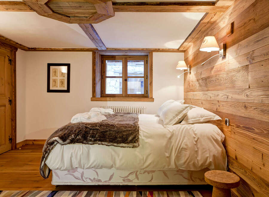 Experience rustic charm in this cozy bedroom, featuring a stunning wooden accent wall and exposed beams.