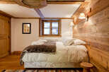 Experience rustic charm in this cozy bedroom, featuring a stunning wooden accent wall and exposed beams.