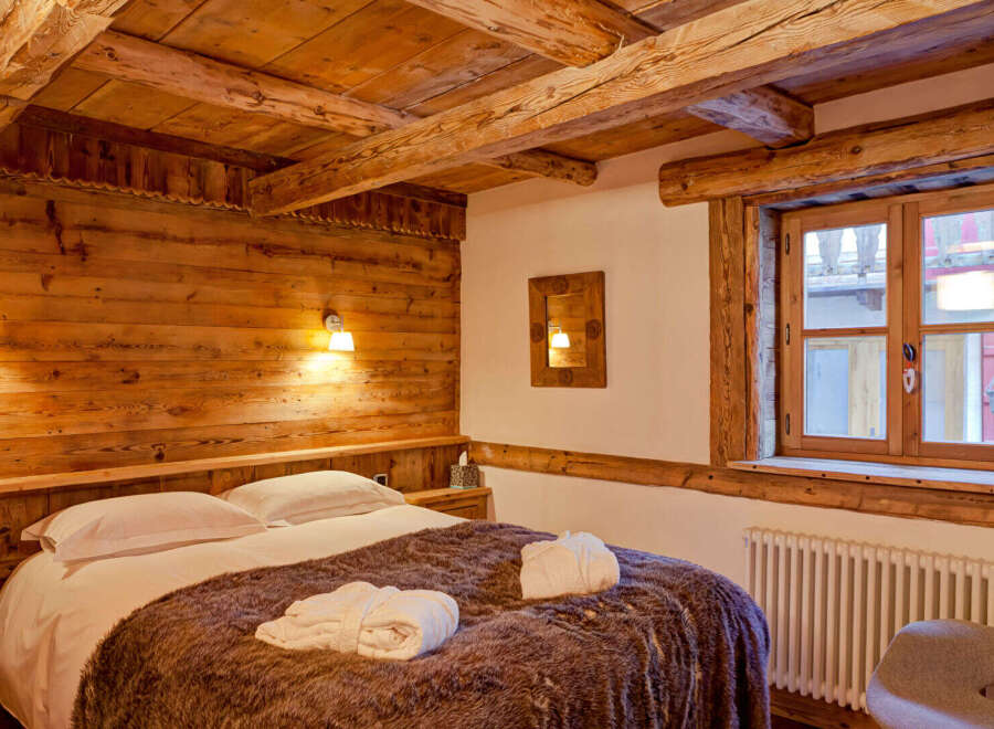 Experience rustic charm in this cozy bedroom featuring exposed wooden beams and walls.