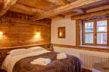 Experience rustic charm in this cozy bedroom featuring exposed wooden beams and walls.