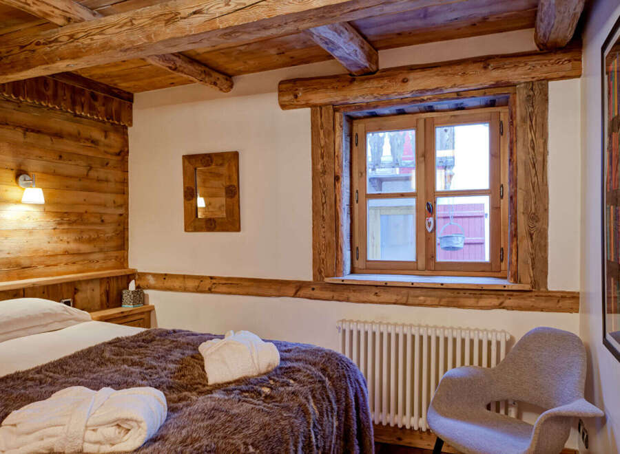 Experience rustic charm in this cozy bedroom featuring exposed wooden beams and a warm, inviting atmosphere.