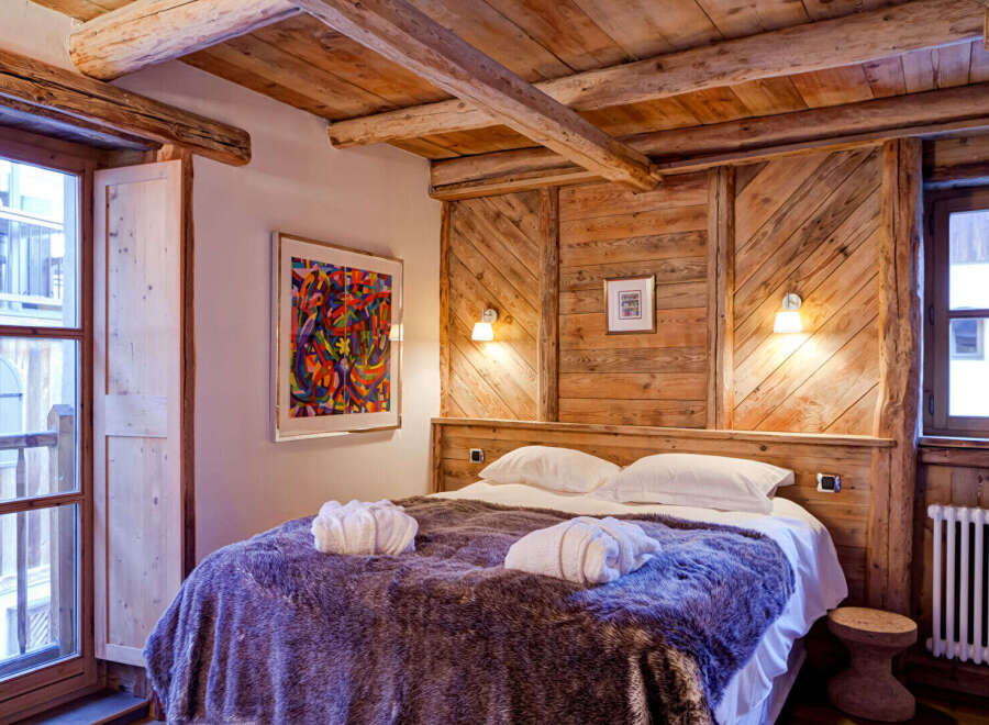 Experience rustic charm in this cozy bedroom, featuring a stunning wooden headboard and ceiling beams.