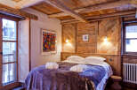 Experience rustic charm in this cozy bedroom, featuring a stunning wooden headboard and ceiling beams.