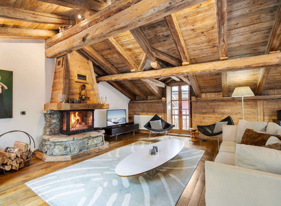 Experience rustic luxury in this stunning living room, featuring a magnificent stone fireplace and exposed wooden beams that create a warm, inviting ambiance.