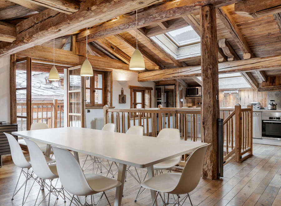 Experience rustic charm in this stunning dining area, featuring exposed wooden beams and a large white dining table perfect for gatherings.