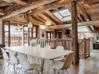 Experience rustic charm in this stunning dining area, featuring exposed wooden beams and a large white dining table perfect for gatherings.
