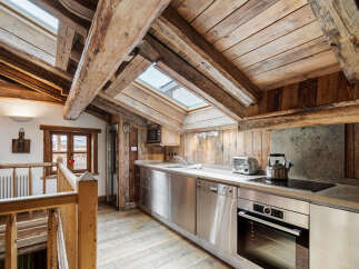 Experience rustic charm in this mountain chalet kitchen, featuring exposed wooden beams and a sloped ceiling with skylights that flood the space with natural light.