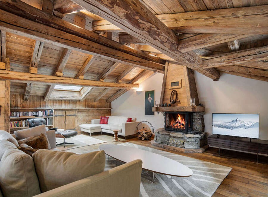 Experience rustic luxury in this stunning living room, featuring exposed wooden beams and a magnificent stone fireplace.
