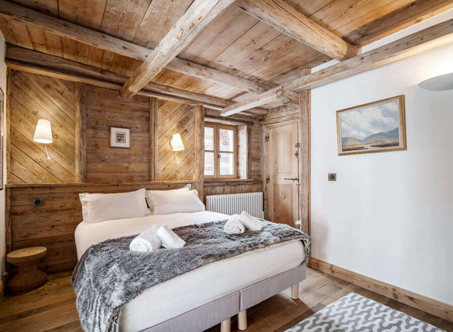 Experience rustic charm in this cozy bedroom featuring exposed wooden beams and walls, creating a warm and inviting alpine atmosphere.