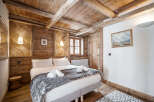 Experience rustic charm in this cozy bedroom featuring exposed wooden beams and walls, creating a warm and inviting alpine atmosphere.