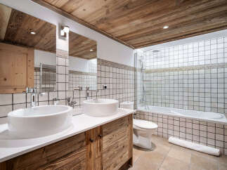Experience rustic charm in this mountain-inspired bathroom, featuring a double vanity with vessel sinks and warm wooden cabinetry.