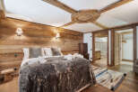 Experience rustic luxury in this charming bedroom, featuring warm wooden walls and exposed beams for a cozy alpine ambiance.