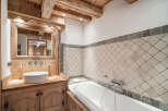 Experience rustic charm in this mountain bathroom, featuring a wooden vanity with a vessel sink and a large mirror framed by exposed beams.