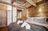 Experience rustic charm in this cozy bedroom featuring exposed wooden beams and a plush, fur-covered bed.