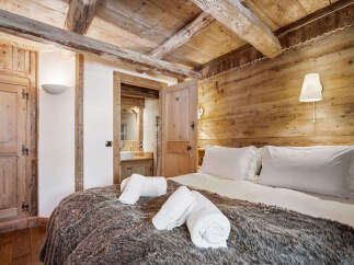 Experience rustic charm in this cozy bedroom featuring exposed wooden beams and a plush, fur-covered bed.