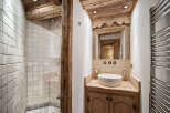 Experience rustic charm in this mountain bathroom, featuring a spacious walk-in shower with textured tile and a wooden beam accent.