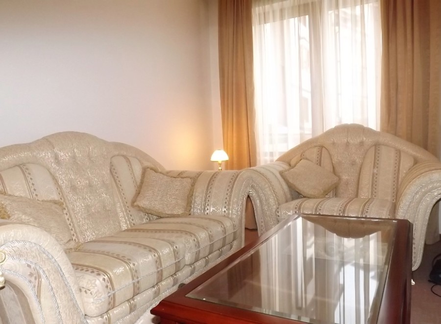 Relax in style in this elegant living room, featuring a plush sofa and armchair, perfect for unwinding after a long day.