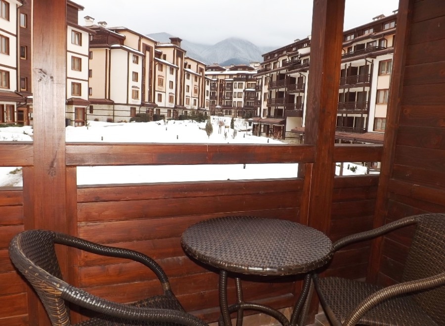 Enjoy breathtaking mountain views from your private balcony, complete with cozy wicker furniture and a small table.