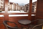 Enjoy breathtaking mountain views from your private balcony, complete with cozy wicker furniture and a small table.