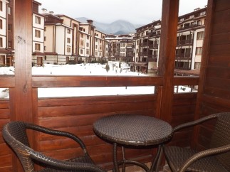 Enjoy breathtaking mountain views from your private balcony, complete with cozy wicker furniture and a small table.