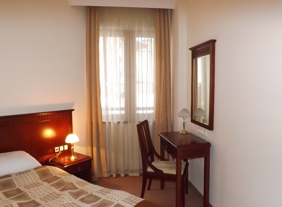 Relax in this cozy hotel room featuring a comfortable bed, a convenient work desk, and a large mirror.