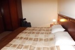 Relax in this cozy hotel room featuring a comfortable double bed with a patterned duvet and plush pillows.