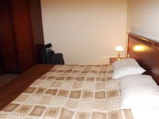 Relax in this cozy hotel room featuring a comfortable double bed with a patterned duvet and plush pillows.