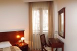 Relax in this well-lit hotel room featuring a comfortable bed, a convenient work desk with chair, and a large mirror.