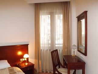 Relax in this well-lit hotel room featuring a comfortable bed, a convenient work desk with chair, and a large mirror.