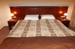 This hotel room features a comfortable double bed with a patterned bedspread and a rich brown headboard.