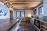 This charming kitchen boasts a rustic design with wooden cabinets, a wooden ceiling, and a long wooden dining table.