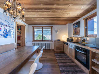 This charming kitchen boasts a rustic design with wooden cabinets, a wooden ceiling, and a long wooden dining table.