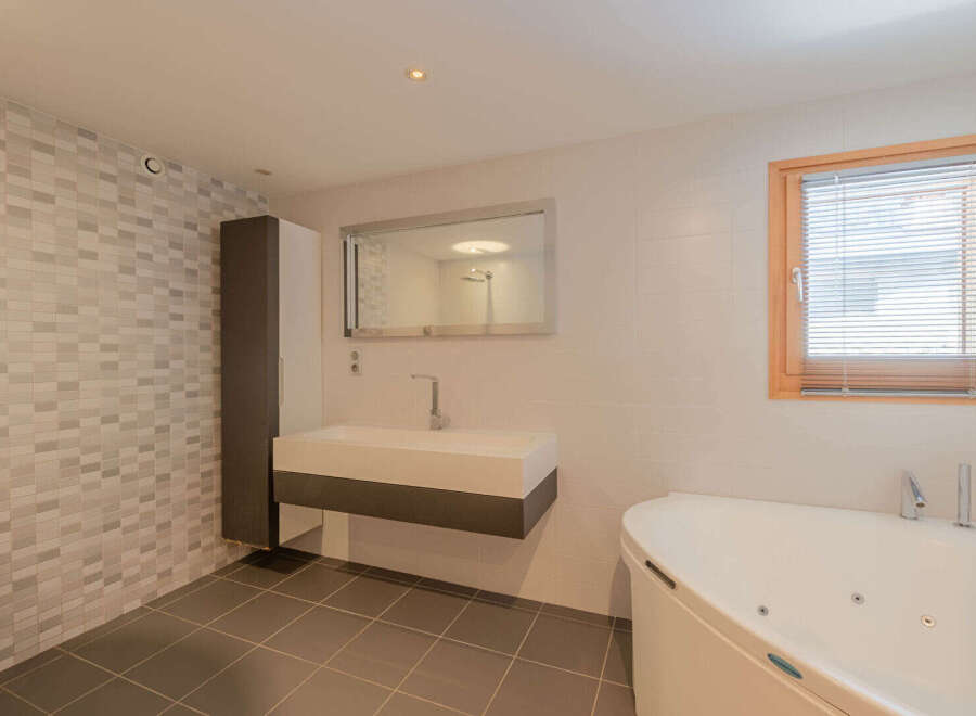 This modern bathroom features a sleek design with a floating vanity and a luxurious soaking tub.