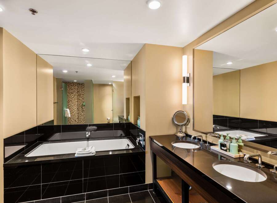 Indulge in luxury within this stunning bathroom, featuring a sleek black tile floor and a modern soaking tub.