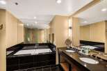 Indulge in luxury within this stunning bathroom, featuring a sleek black tile floor and a modern soaking tub.