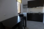 This cozy studio apartment features a well-equipped kitchenette with dark wood cabinets and a small refrigerator.