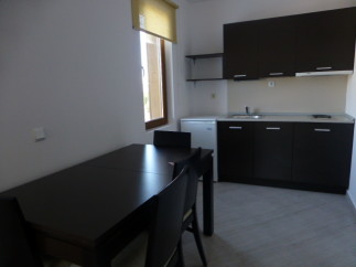 This cozy studio apartment features a well-equipped kitchenette with dark wood cabinets and a small refrigerator.