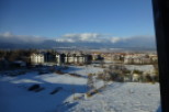 Snow covered landscape with mountain views and residential buildings.