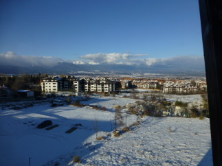 Snow covered landscape with mountain views and residential buildings.