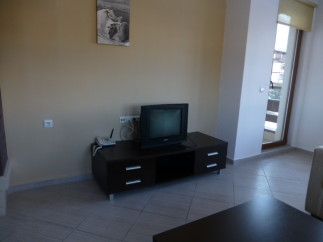 Cozy living room with tiled floors and a dark brown media console featuring a TV and drawers.