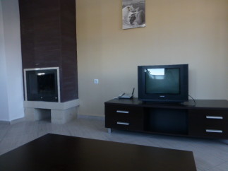 Cozy living room featuring a modern fireplace and dark wood entertainment center with TV.