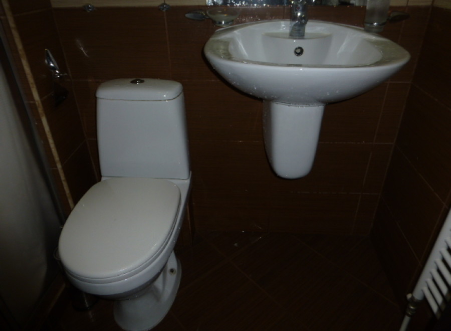 This cozy bathroom boasts a modern toilet and a stylish wall-mounted sink, perfect for a quick refresh.