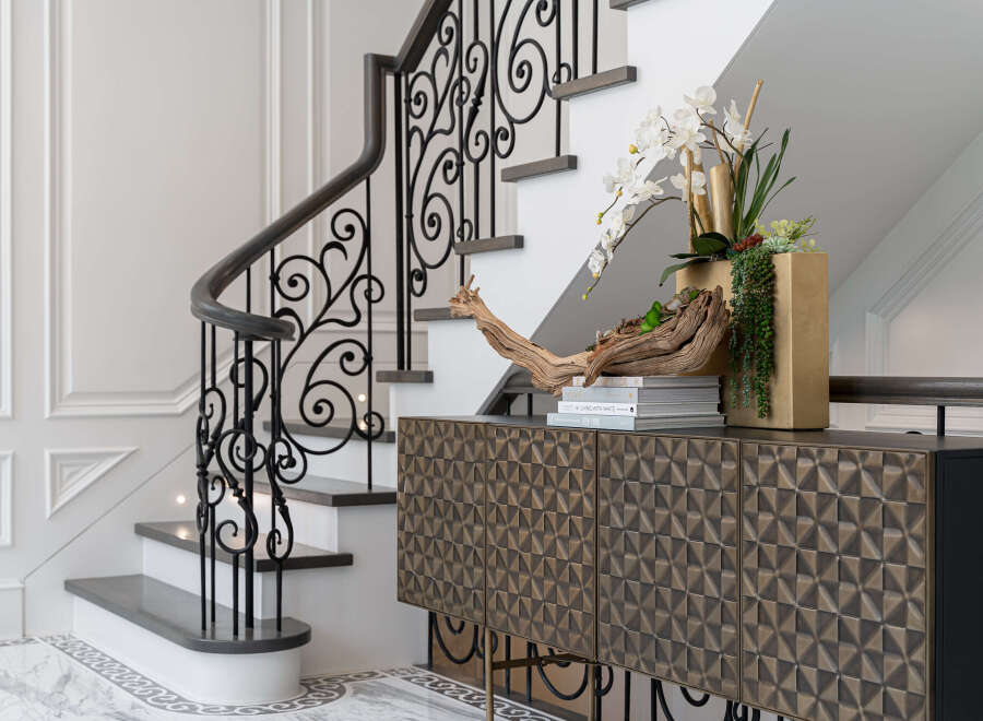 This stunning entryway showcases a beautifully designed staircase with intricate wrought iron detailing, leading to the upper levels of the home.